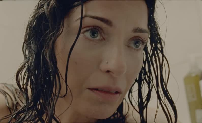 A woman with wet hair looks around nervously