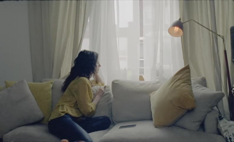 A teen sits on a couch and looks out the window