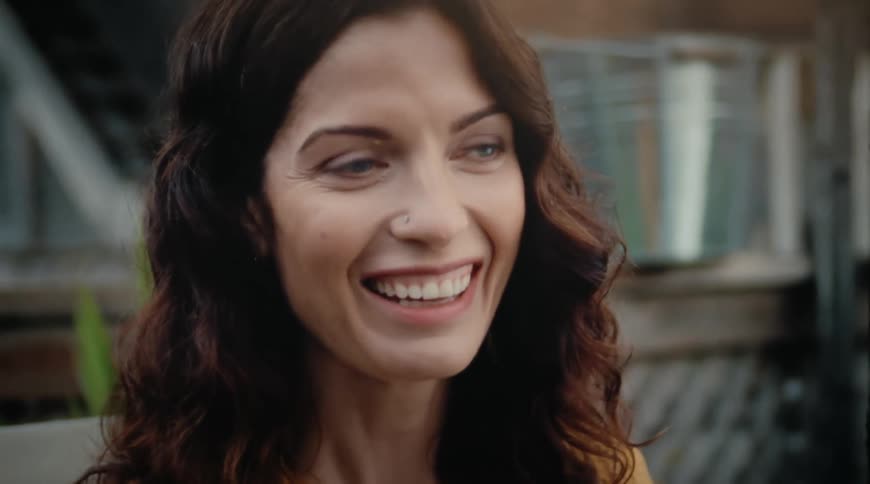 A woman is smiling outdoors during midday