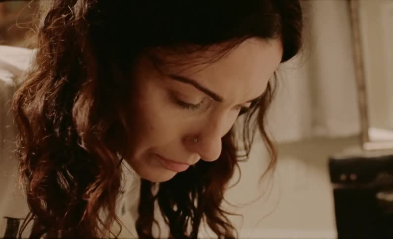 A woman with her head hanging grimaces and sniffles as she tries not to cry