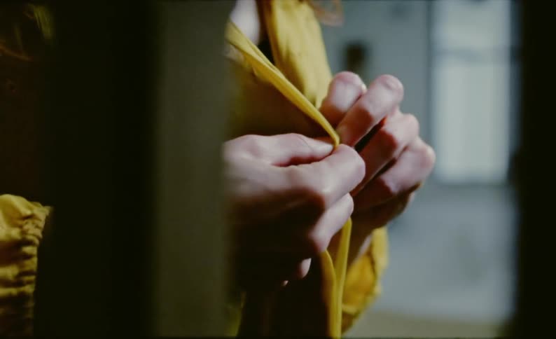 A woman tries to close a button on a blouse but has trouble and gets frustrated