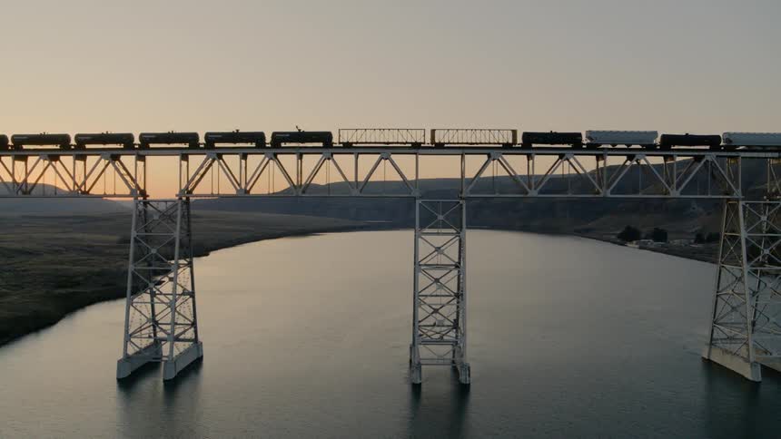 Traveling parallel with a cargo train as it moves across a high bridge over water