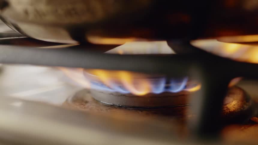 A gas burner flaming on high heating a heavy pot