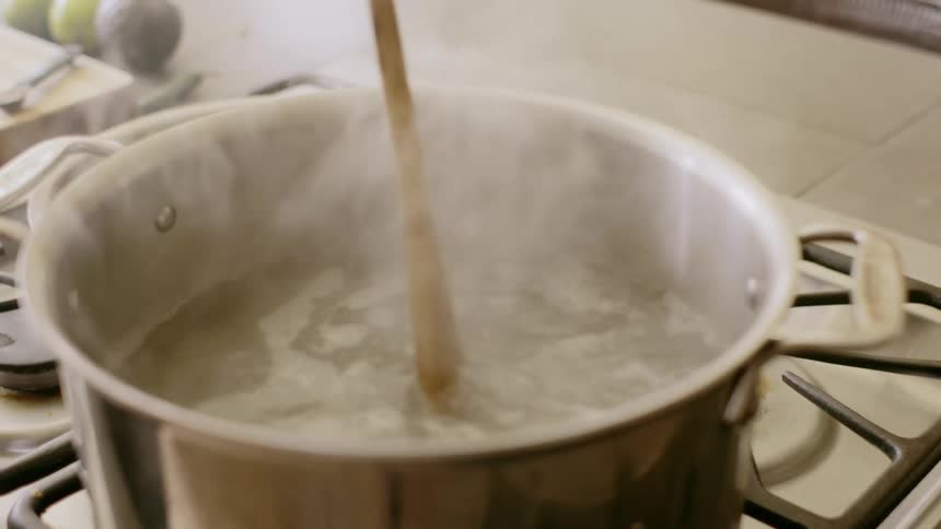 A wooden spoon stirring a boiling pot
