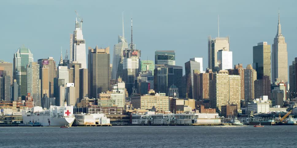 Hospital ship sits docked at waterfront near downtown tower block