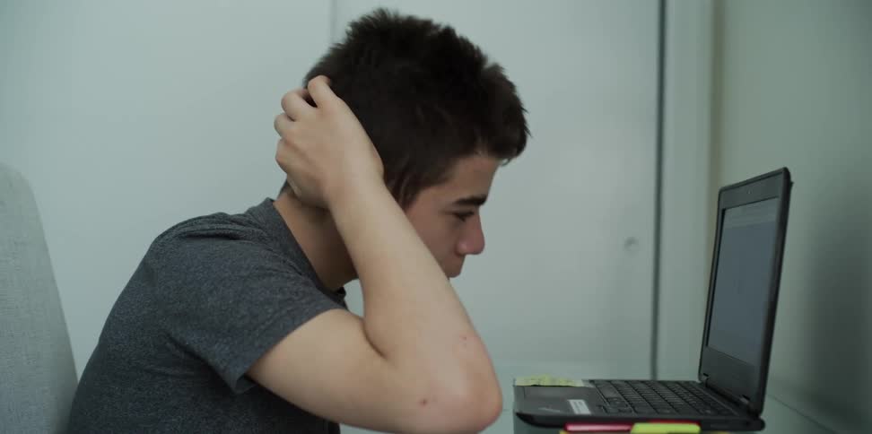Boy working on homework on laptop in bedroom
