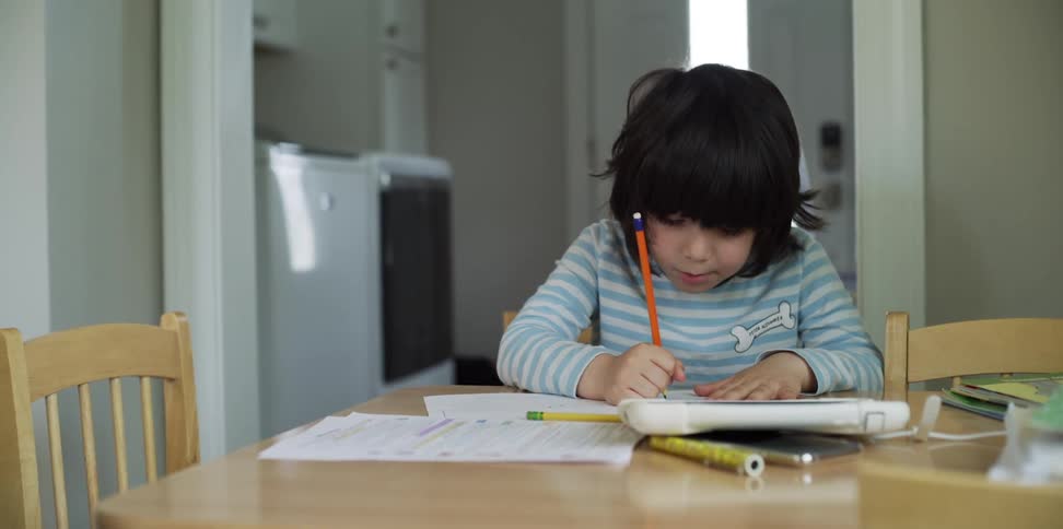 A child writes while sitting at a kitchen table