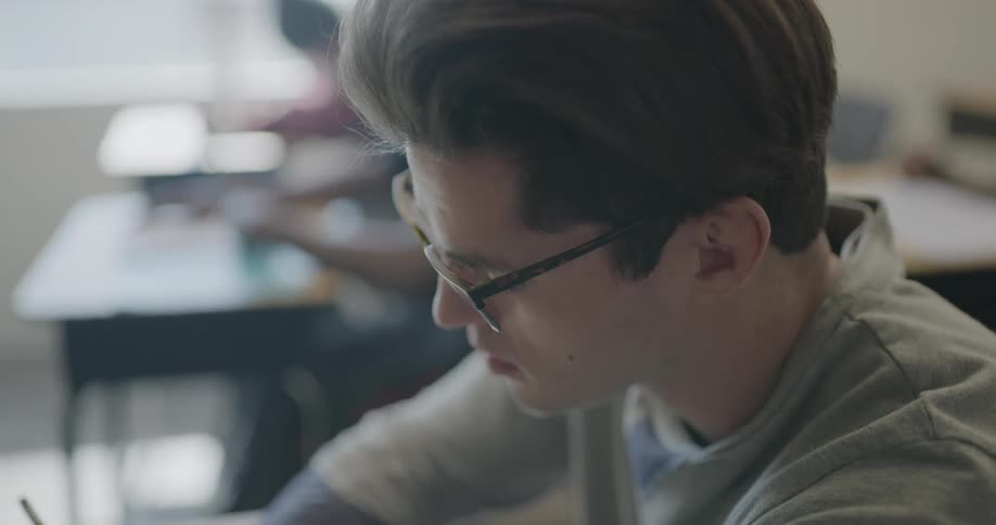 Male student taking notes in a classroom