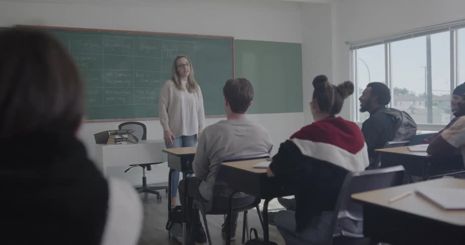 A teacher stands at the front of a classroom and instructs her students