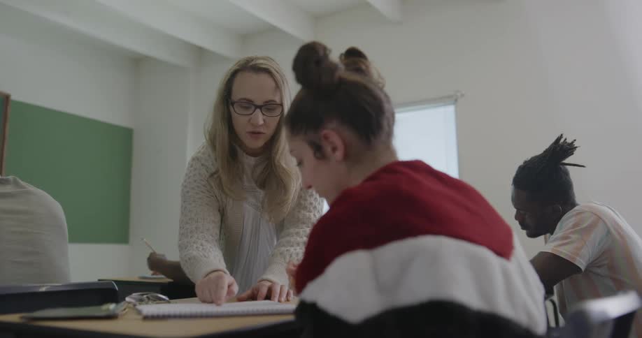 Students write in their notebooks as a teacher instructs them