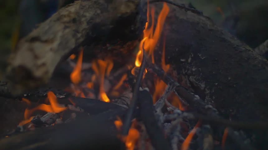 An outdoor fire burns and smokes