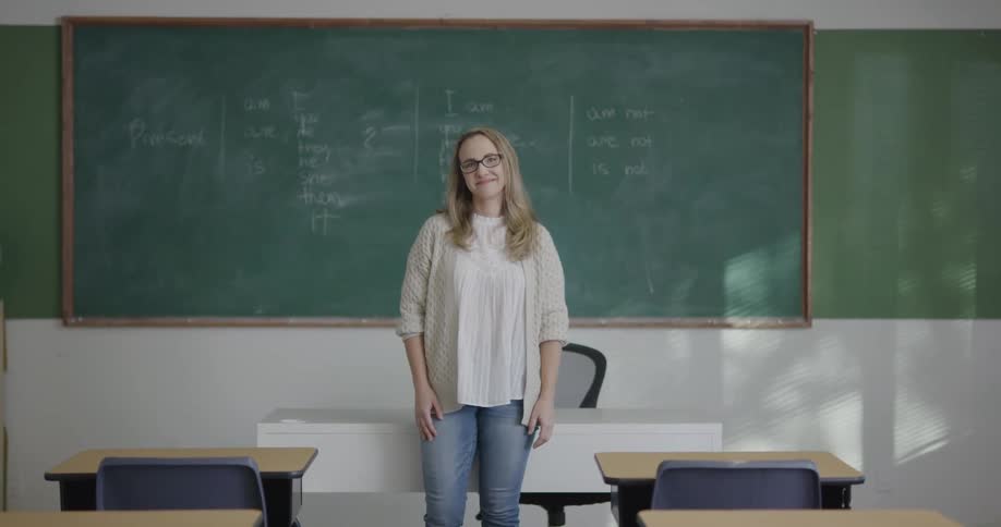 Teacher standing in front of blackboard in classroom at day