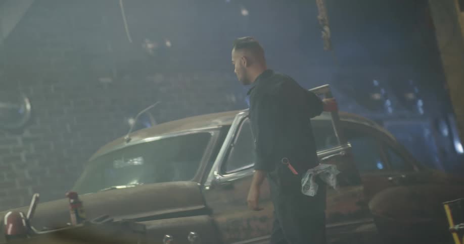 A mechanic lifts up the hood of a car