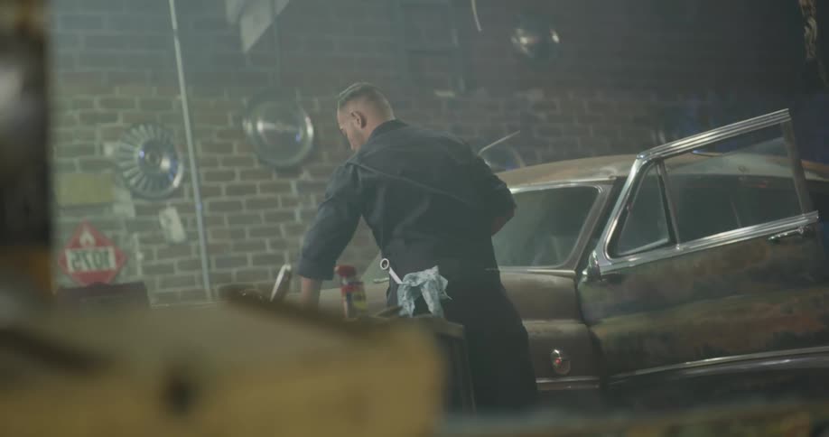 Mechanic working on vintage car engine in workshop