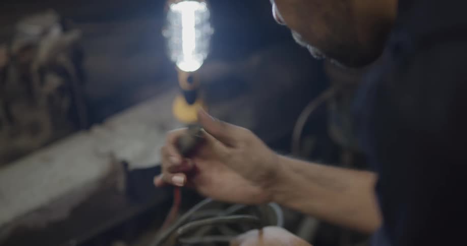 A mechanic examines wires