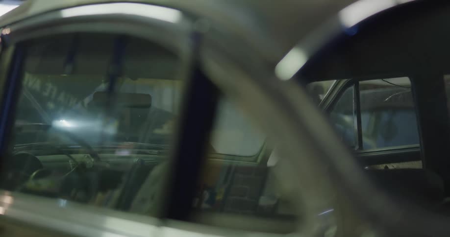 Mechanic repairs vintage car inside workshop