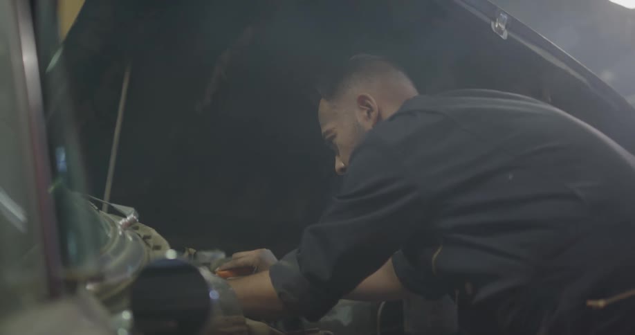 A mechanic looks under the hood of a car