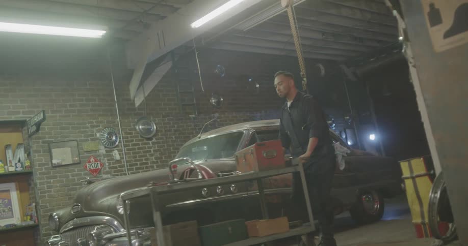 A man pushes a cart toward the hood of the car