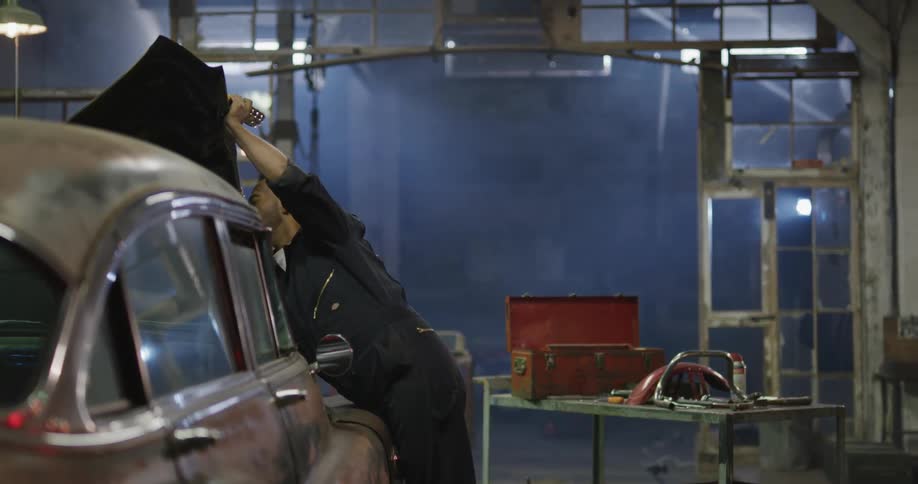 Mechanic working on vintage car engine inside workshop