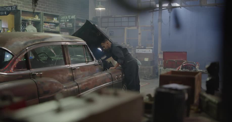 Mechanic inspects car engine using a handheld light