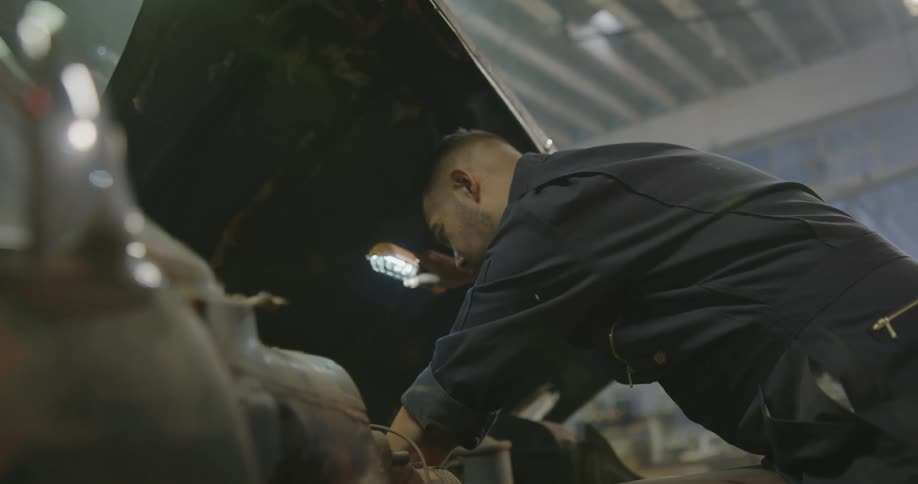 A mechanic looking inside an old car