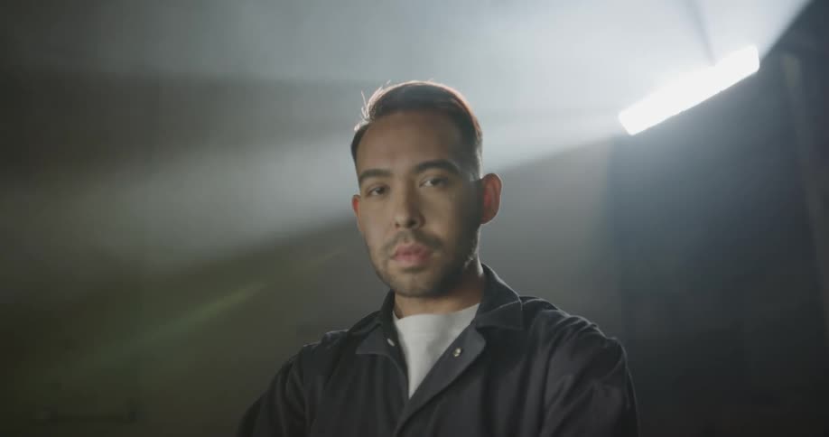 A mechanic stands inside with his arms crossed