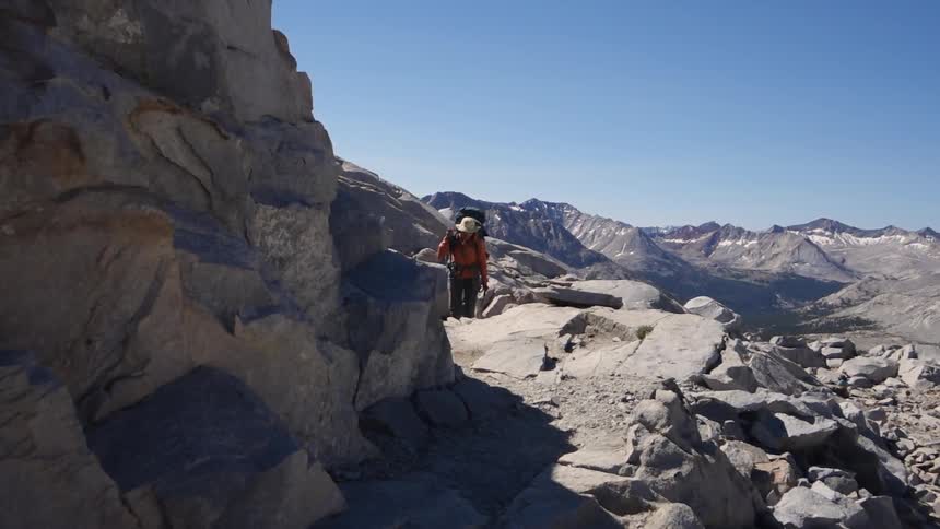 A man is climbing up a mountain on a sunny day