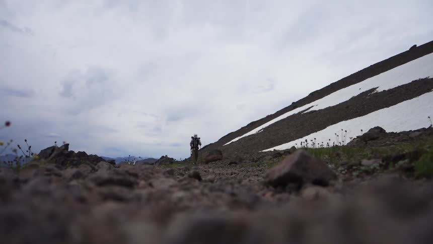 Three people are hiking along the side of a lake