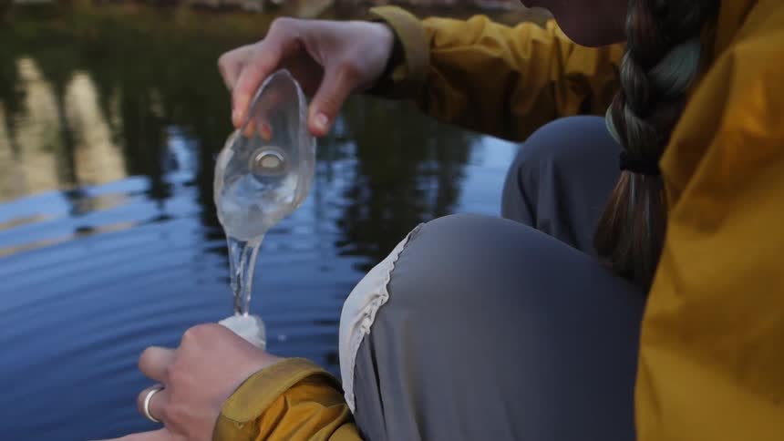 A woman pours lake water into a bottle