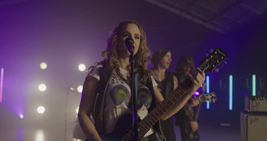 Rock band performs on stage tinted purple by light show