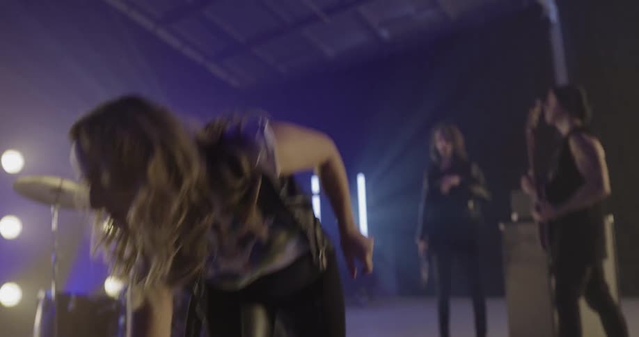 A woman in a band puts down her guitar and talks to her band mates