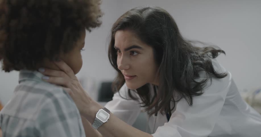 A female doctor examines a young patient and tries to make him laugh