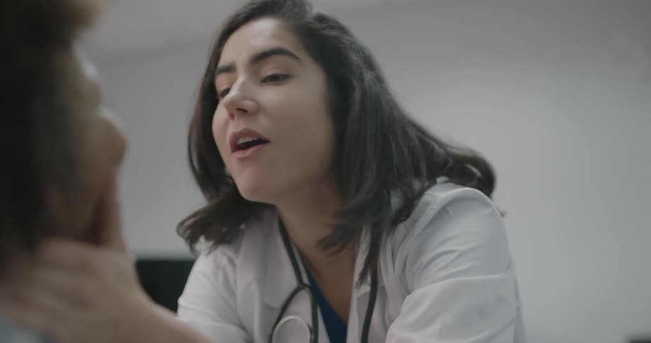 A doctor shows a little boy how wide to open his mouth so she can examine him