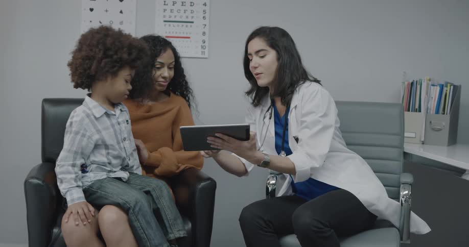 A doctor showing and explaining a tablet to a woman and her son