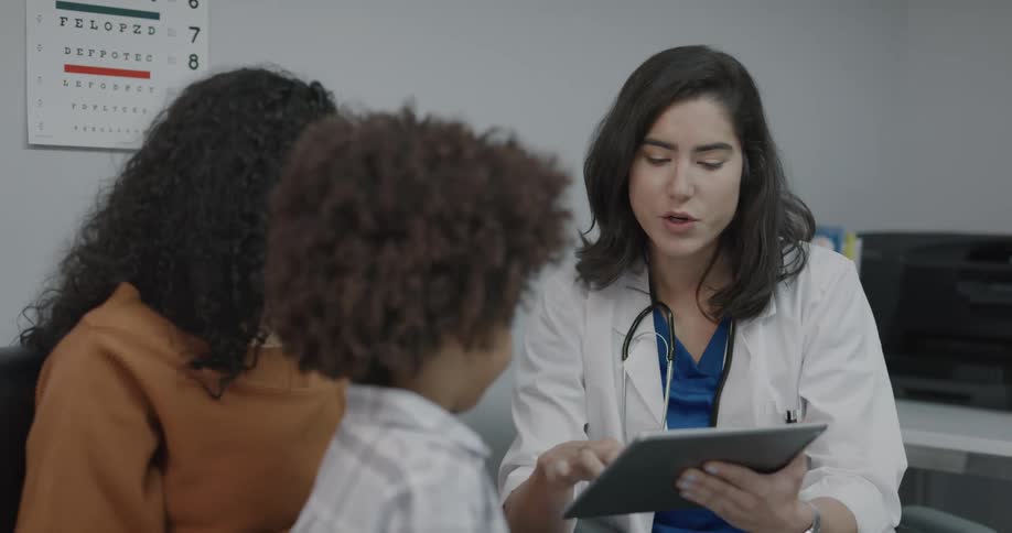 Doctor explains diagnosis to mother referencing tablet