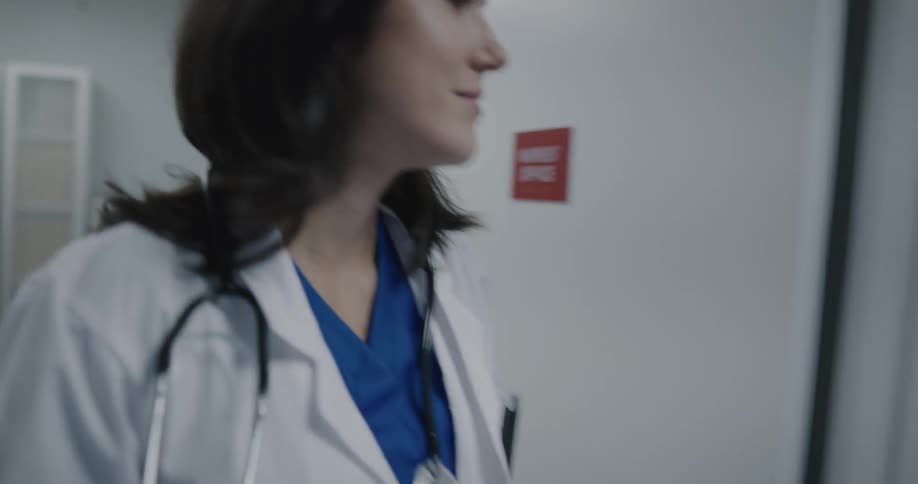 A doctor putting on a lab coat and walking down a hallway