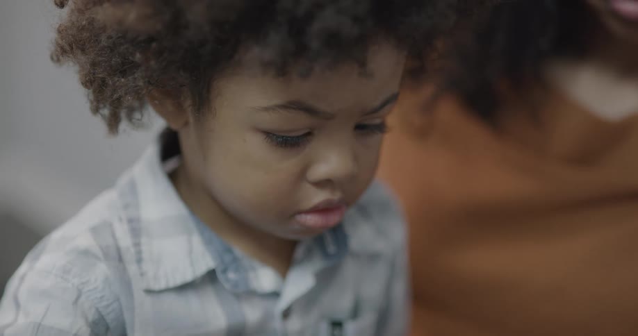 A woman shows a young child how to do things on a tablet