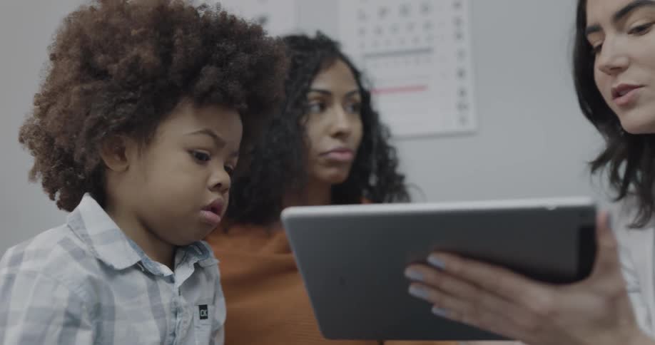A doctor showing and explaining the contents of a tablet to a mother and her son