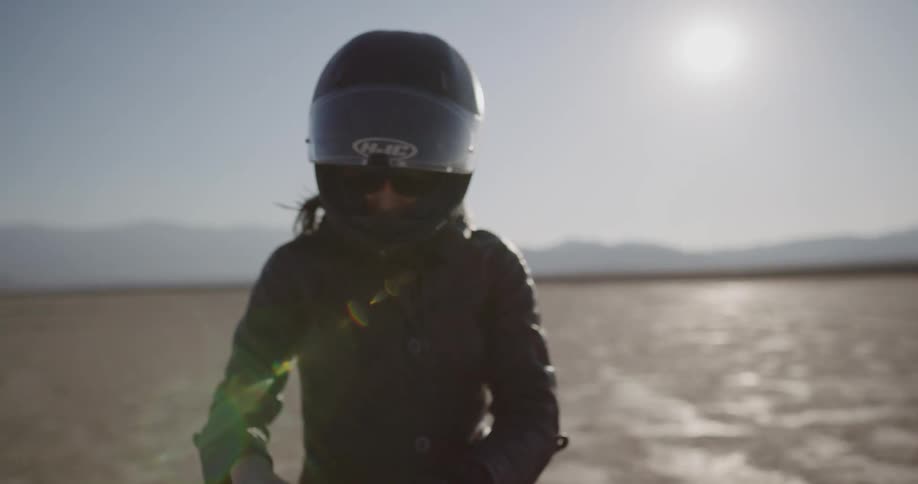A woman suits up to ride her motorcycle in the desert