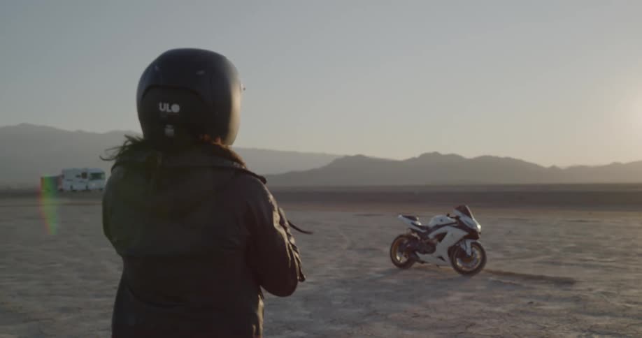 A woman putting on her helmet and walking to her bike