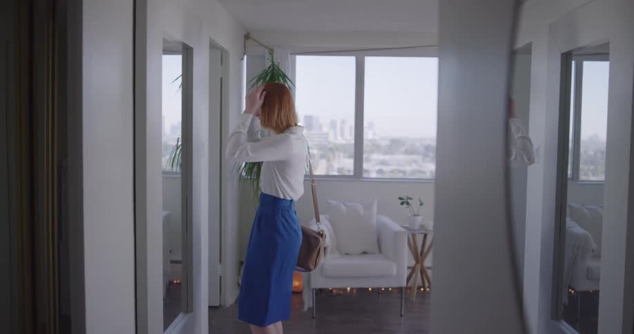 Woman checks herself in the apartment mirror before going out