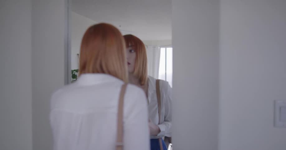 A woman checks her makeup in the mirror before leaving her house