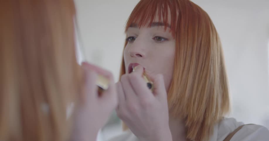 A woman applies lipstick