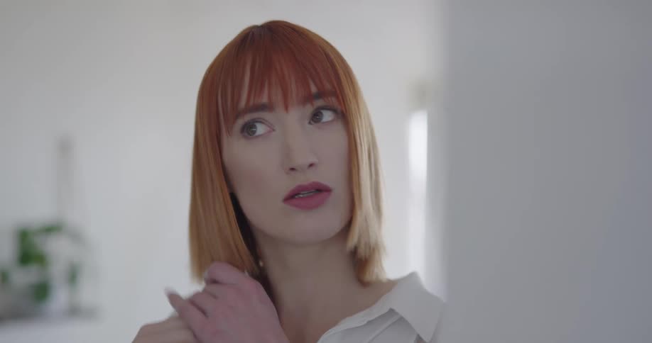 A woman stopping to adjust her hair in a mirror before walking away