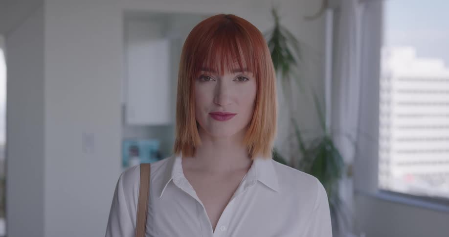 A woman stands in a downtown office on a sunny day and smiles