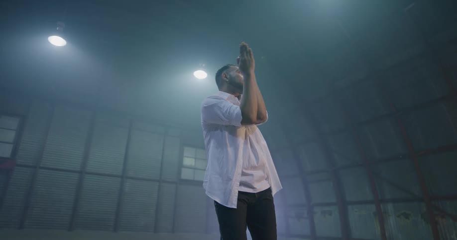 A man dances in a dark room