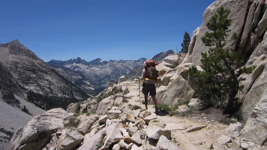 A hiker walks along a rocky mountain side