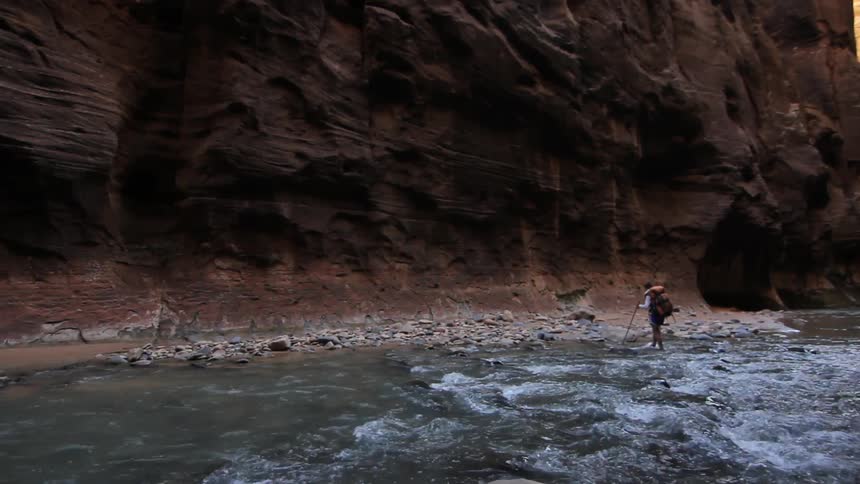 A person hikes through a stream