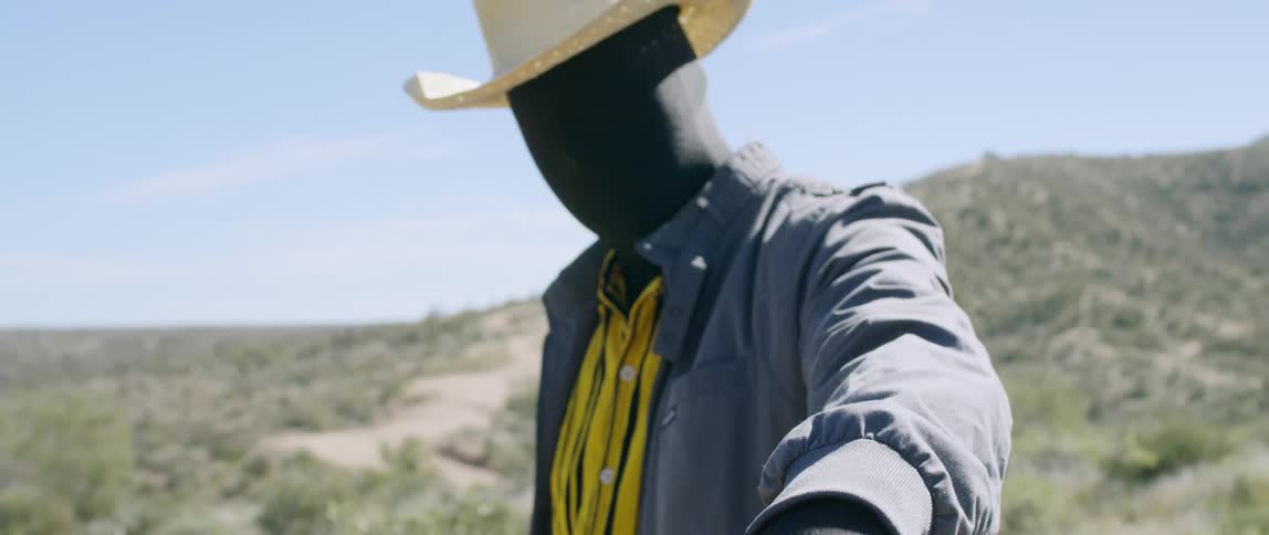 A man dressed as a scarecrow drops his arm down to his side