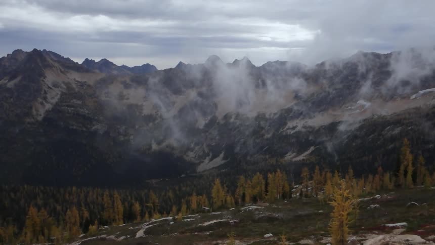 Wispy clouds floating over the tops of trees in the mountains on a cloudy day